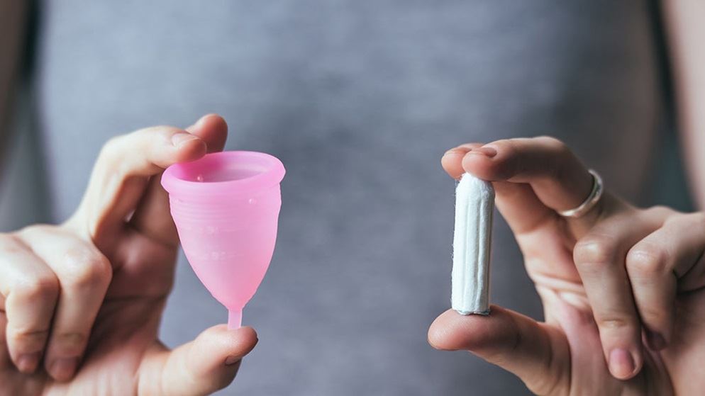 woman holding menstrual cup and tampon